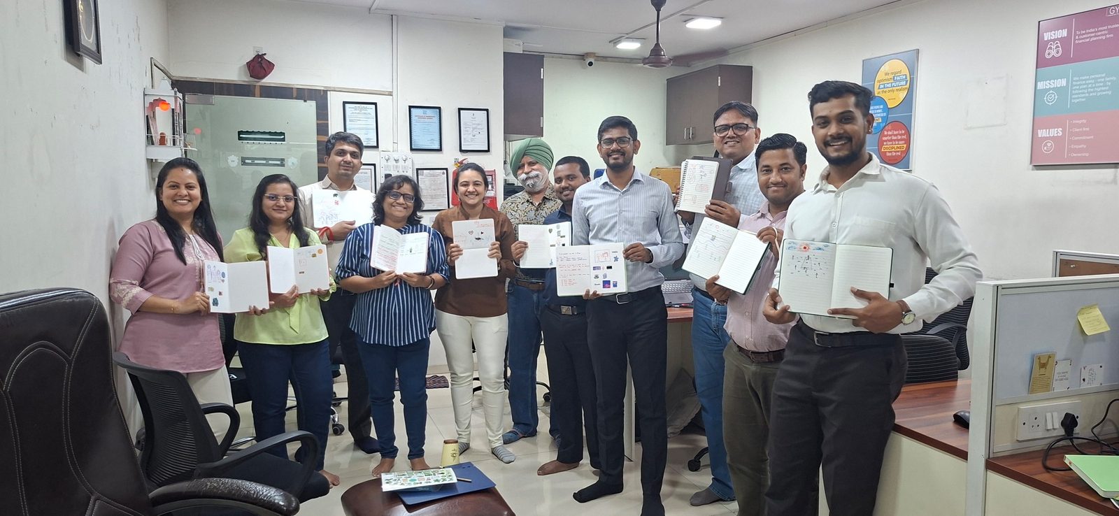 About a dozen members of the GYR team stand together in the office after a journaling session, smiling and holding open notebooks. Posters of the firm’s vision, mission and values hang on the wall.